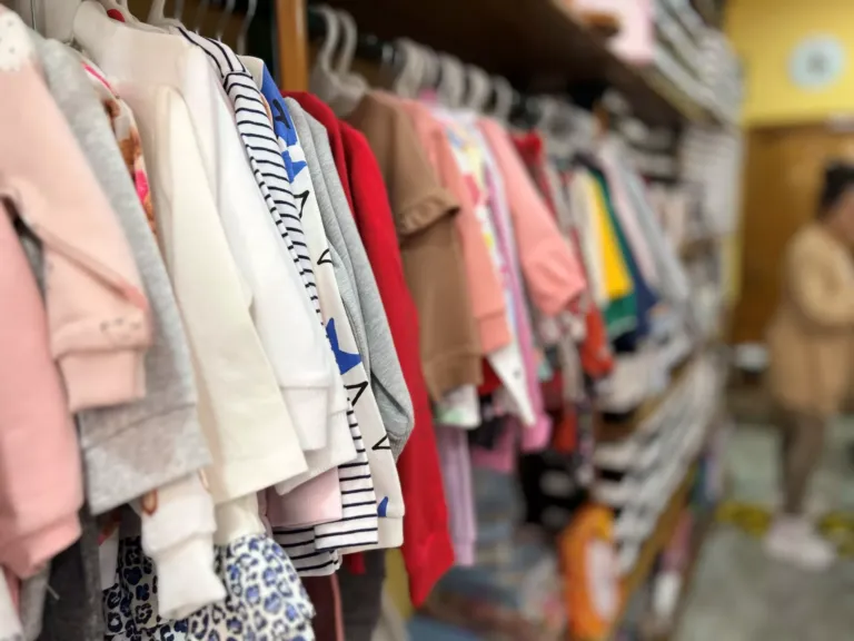 Numerosas prendas de vestir para niños colgadas en perchas